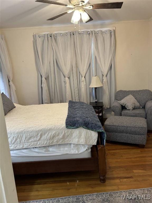 bedroom featuring ceiling fan, ornamental molding, and wood-type flooring