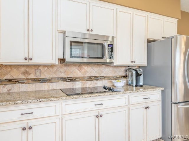 kitchen featuring white cabinetry, decorative backsplash, light stone countertops, and stainless steel appliances