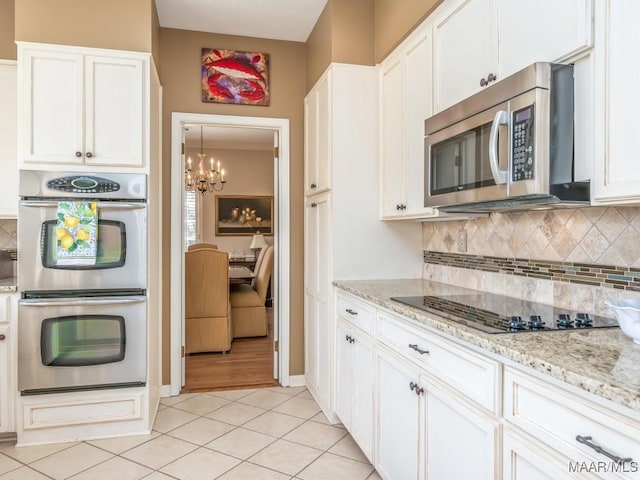 kitchen with backsplash, white cabinetry, light stone countertops, light tile patterned flooring, and stainless steel appliances