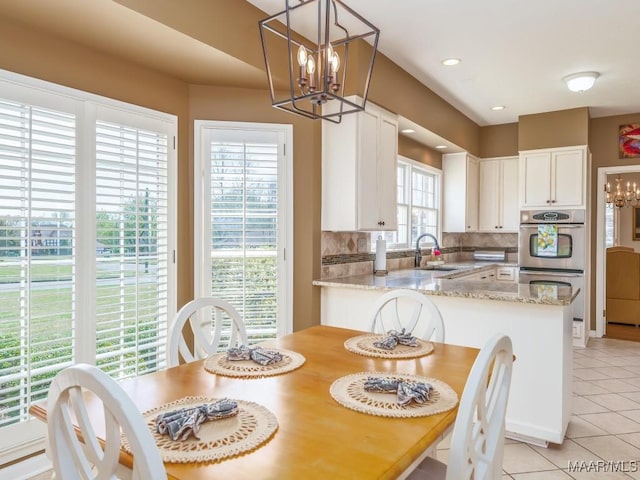 tiled dining room featuring sink, a chandelier, and a wealth of natural light