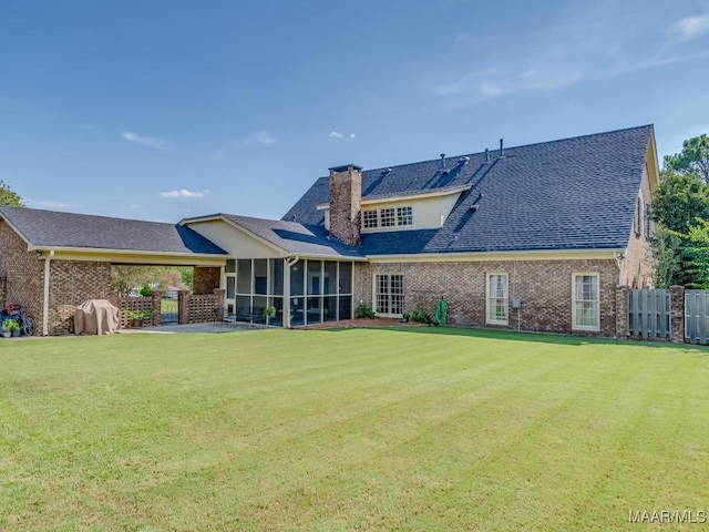 rear view of property with a sunroom, a lawn, and a patio