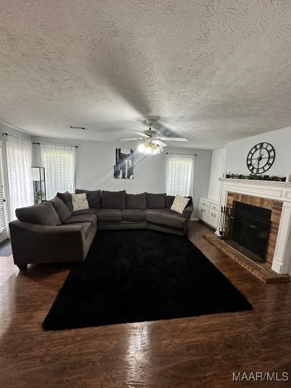 living room featuring a fireplace, a textured ceiling, and ceiling fan