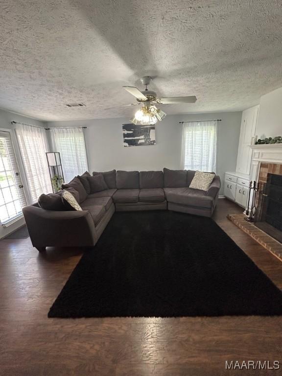 living room with a textured ceiling, a tile fireplace, and a healthy amount of sunlight