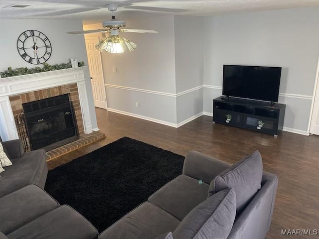 living room with ceiling fan, a brick fireplace, and dark hardwood / wood-style flooring