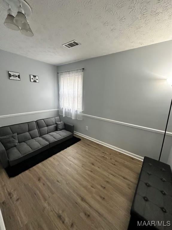 unfurnished living room with dark wood-type flooring and a textured ceiling