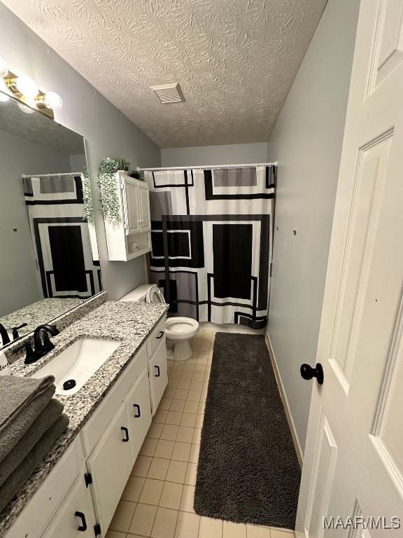 bathroom featuring toilet, a textured ceiling, tile patterned flooring, vanity, and a shower with curtain