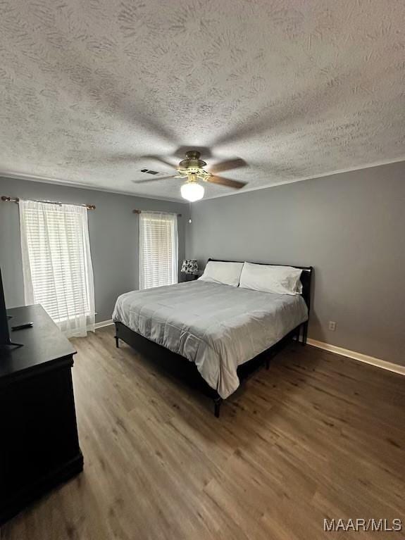 bedroom with wood-type flooring, multiple windows, a textured ceiling, and ceiling fan