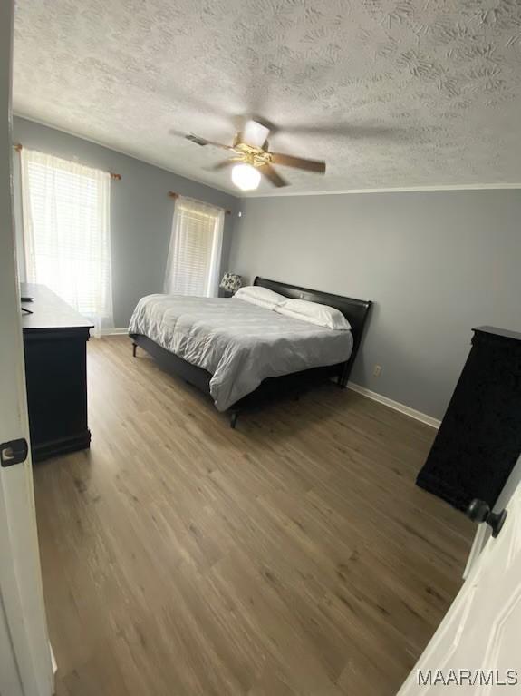 bedroom with hardwood / wood-style floors, a textured ceiling, and ceiling fan