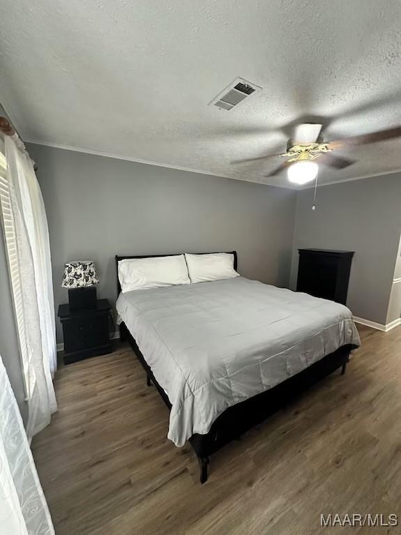 bedroom featuring ceiling fan, dark wood-type flooring, and a textured ceiling