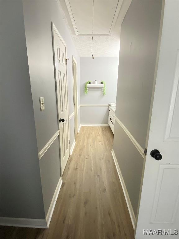 hallway with light hardwood / wood-style floors and ornamental molding