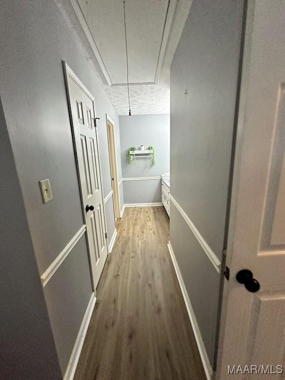 hallway featuring wood-type flooring, a textured ceiling, and crown molding