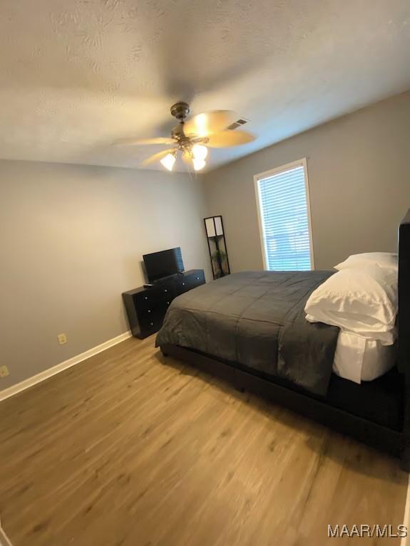 bedroom with ceiling fan and hardwood / wood-style flooring