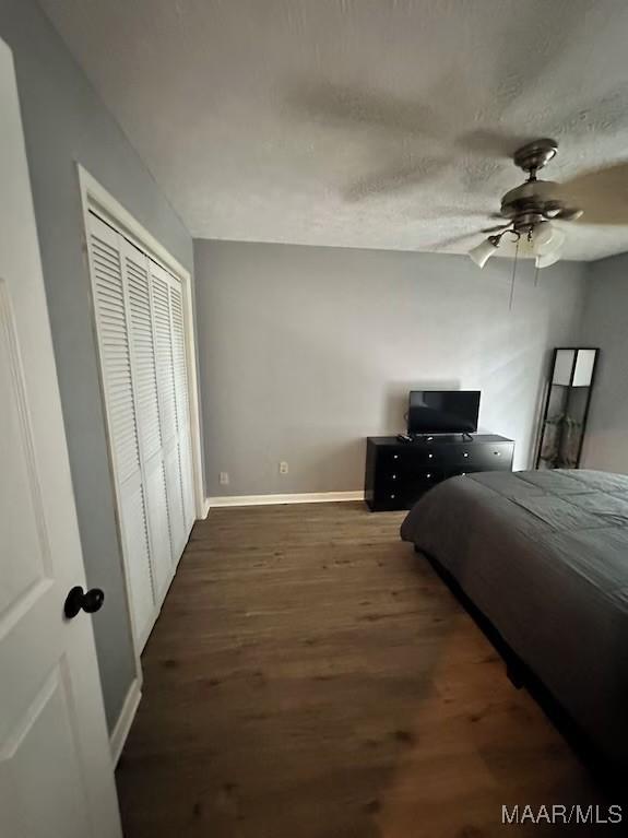 bedroom with a textured ceiling, a closet, ceiling fan, and dark hardwood / wood-style flooring