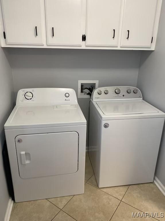 laundry room featuring washer and clothes dryer, cabinets, and light tile patterned floors