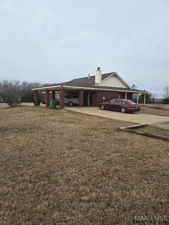 exterior space with a carport and a lawn