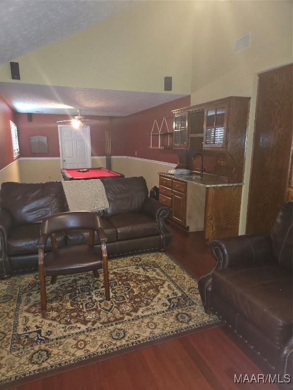 living room featuring sink, dark hardwood / wood-style floors, and vaulted ceiling