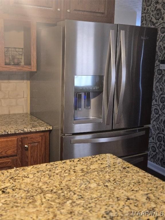 kitchen featuring light stone counters, backsplash, and stainless steel fridge with ice dispenser