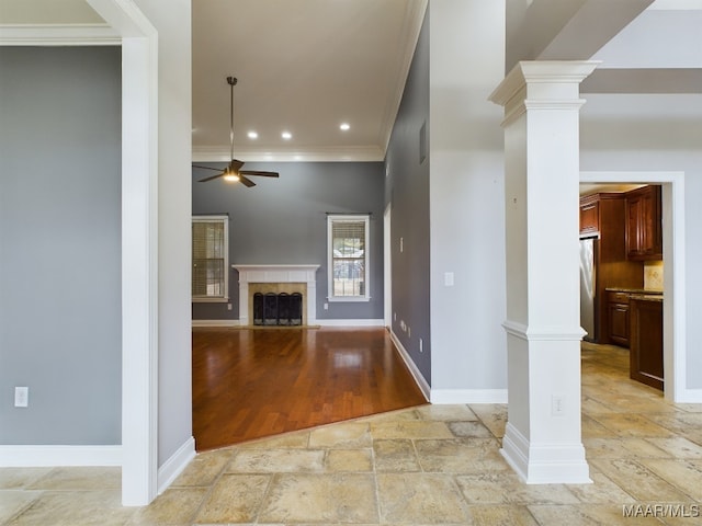 unfurnished living room featuring ceiling fan, ornamental molding, and ornate columns