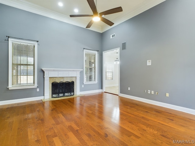 unfurnished living room with hardwood / wood-style flooring, ornamental molding, a high end fireplace, and ceiling fan