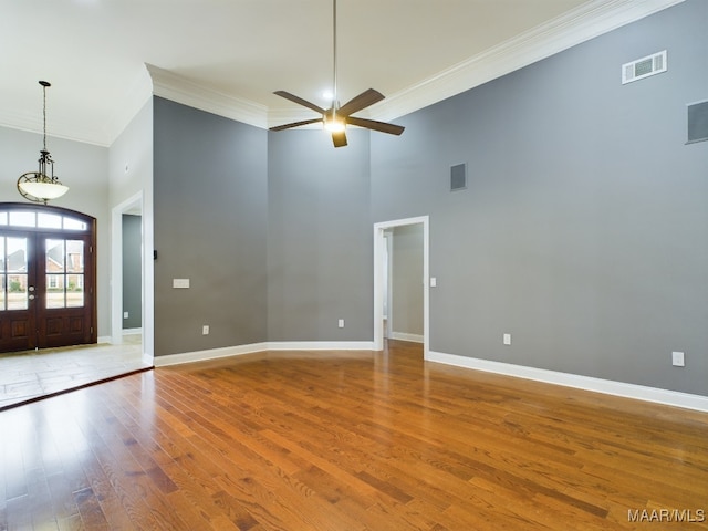 interior space with crown molding, a towering ceiling, hardwood / wood-style floors, and french doors