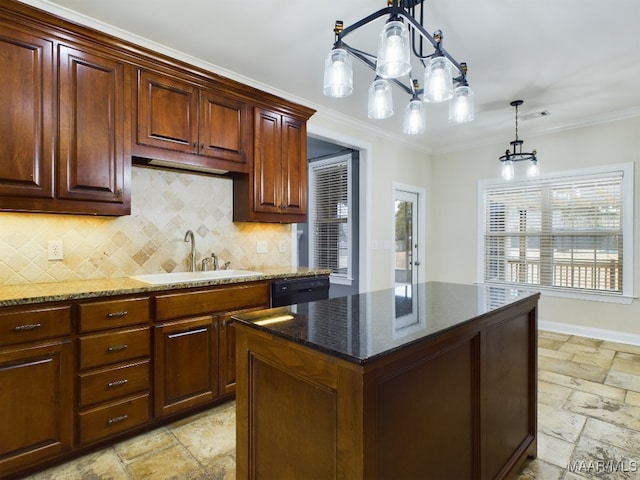 kitchen with decorative light fixtures, sink, dark stone countertops, ornamental molding, and a center island