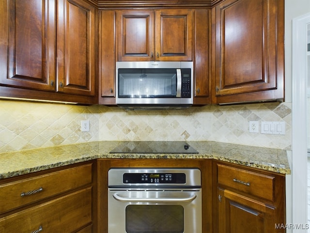 kitchen with light stone countertops, appliances with stainless steel finishes, and backsplash