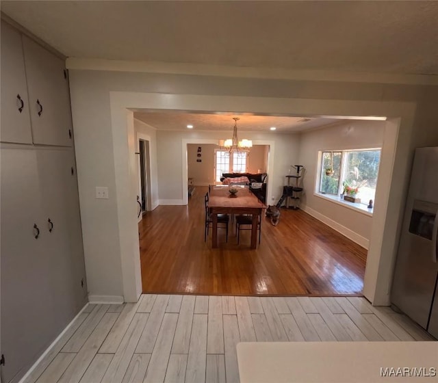 unfurnished dining area with a wealth of natural light, an inviting chandelier, and light hardwood / wood-style flooring