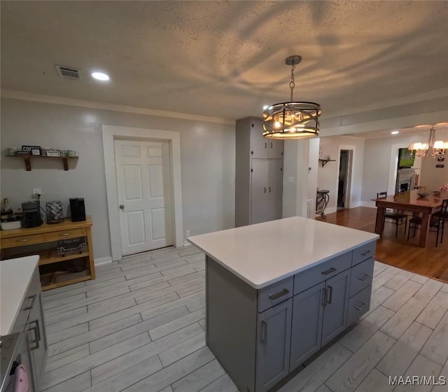 kitchen with hanging light fixtures, crown molding, a center island, and an inviting chandelier