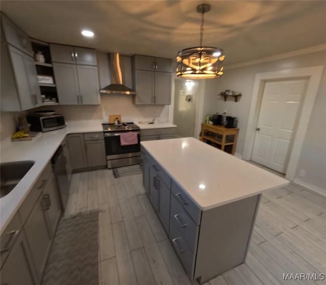 kitchen featuring pendant lighting, gray cabinetry, stainless steel appliances, a kitchen island, and wall chimney exhaust hood