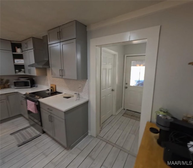 kitchen with gray cabinets, tasteful backsplash, black electric range oven, and wall chimney range hood