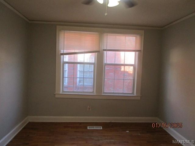 empty room with ceiling fan, dark wood-type flooring, and ornamental molding