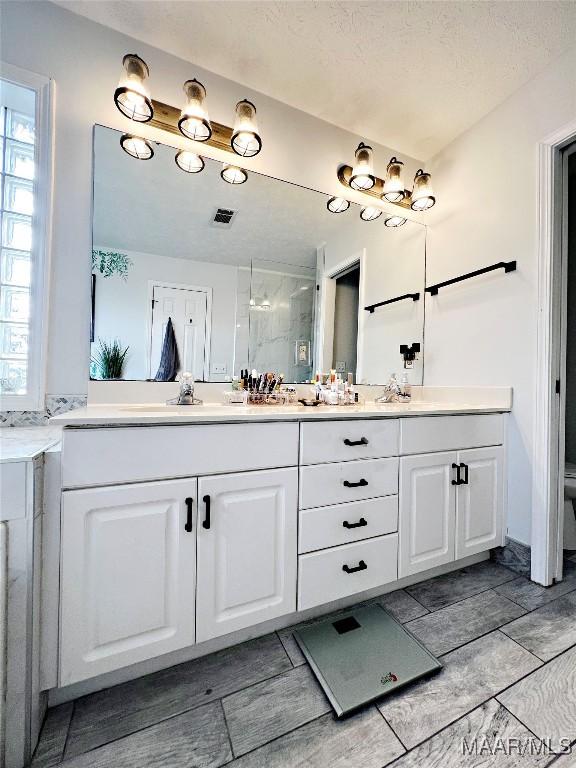 bathroom featuring a textured ceiling, an enclosed shower, and vanity