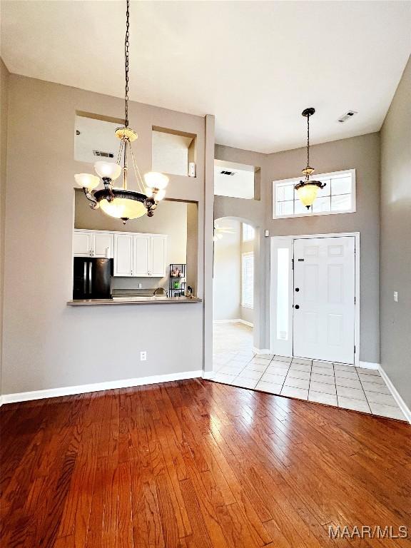 foyer featuring light hardwood / wood-style floors, a chandelier, a high ceiling, and plenty of natural light