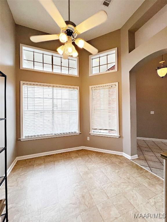 empty room with a towering ceiling and ceiling fan