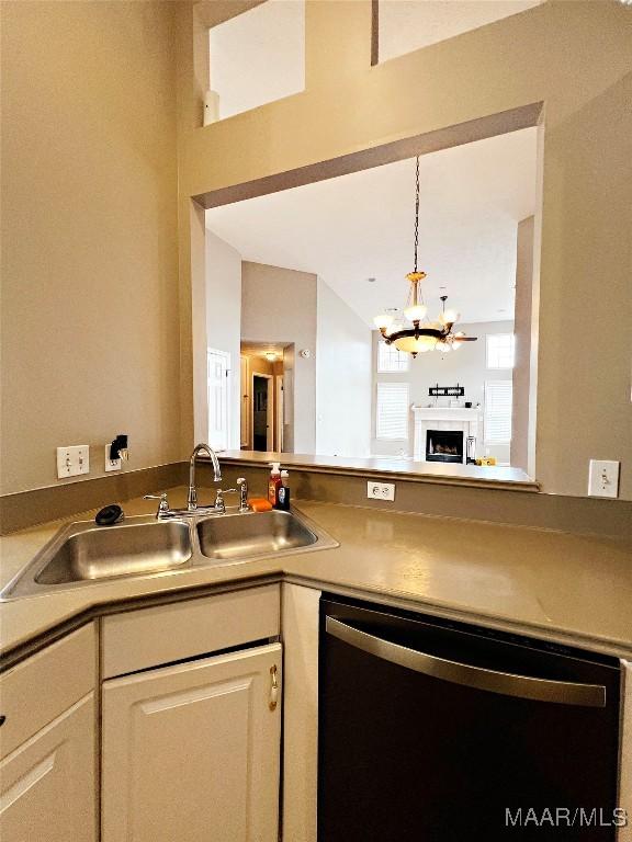 kitchen with sink, dishwashing machine, white cabinets, and a notable chandelier