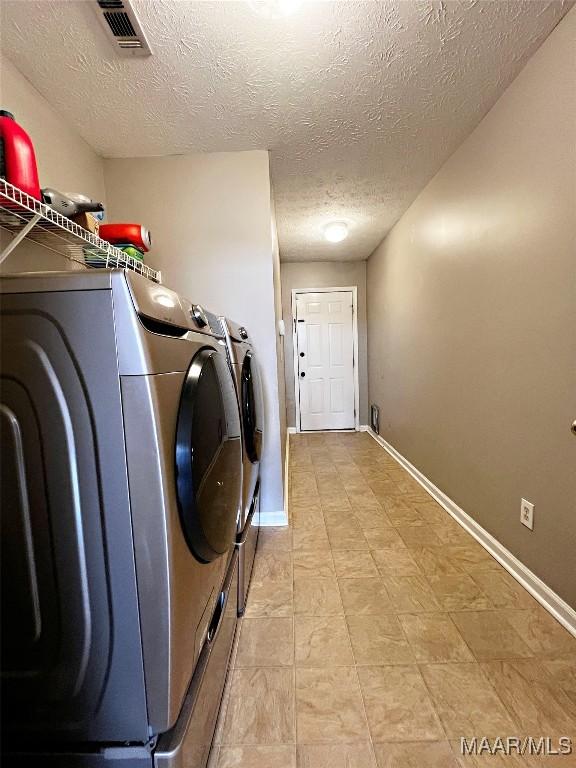 laundry area featuring a textured ceiling and washing machine and clothes dryer