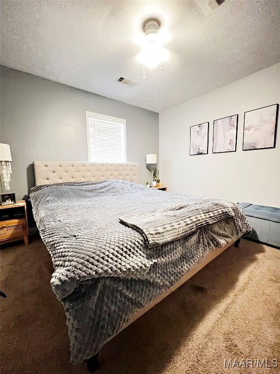 bedroom featuring ceiling fan, carpet, and a textured ceiling