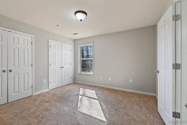 unfurnished bedroom with light carpet and two closets