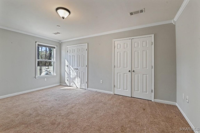 unfurnished bedroom with crown molding, multiple closets, and carpet floors