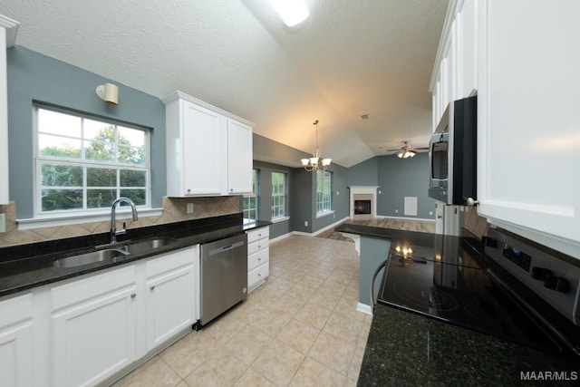 kitchen with appliances with stainless steel finishes, white cabinetry, hanging light fixtures, sink, and lofted ceiling