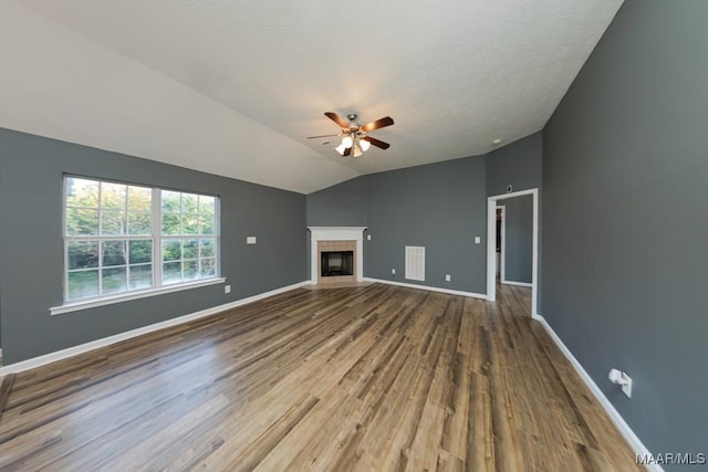 unfurnished living room featuring hardwood / wood-style flooring, a tile fireplace, ceiling fan, and vaulted ceiling