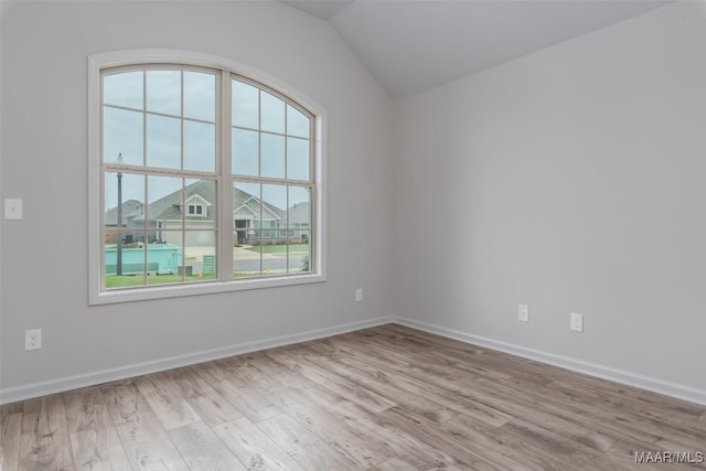 unfurnished room with light hardwood / wood-style floors, vaulted ceiling, and a wealth of natural light