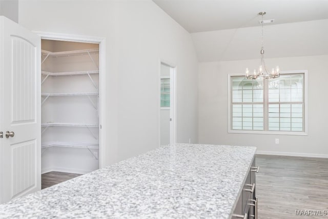 dining area with lofted ceiling, hardwood / wood-style floors, and a notable chandelier