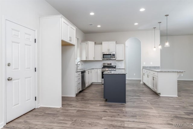 kitchen featuring light stone countertops, appliances with stainless steel finishes, a center island, and white cabinets