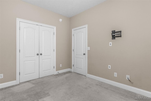 unfurnished bedroom with light colored carpet and a closet