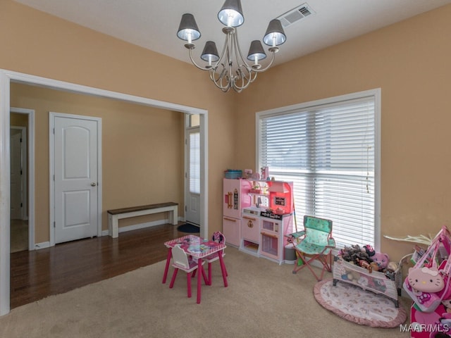 recreation room featuring a notable chandelier and dark colored carpet