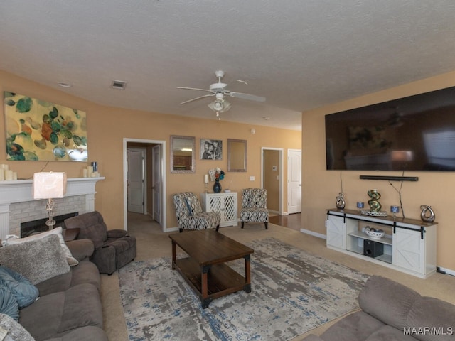 living room featuring ceiling fan, carpet, a textured ceiling, and a brick fireplace