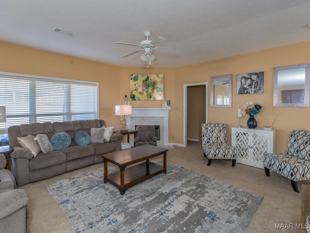 carpeted living room with ceiling fan and a brick fireplace