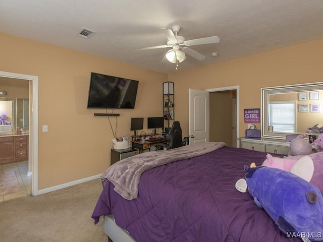 bedroom with ceiling fan, light colored carpet, and ensuite bath