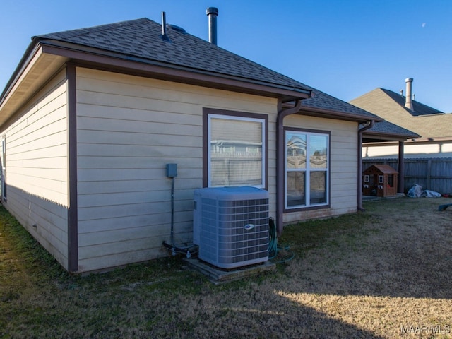 back of house with central air condition unit and a yard